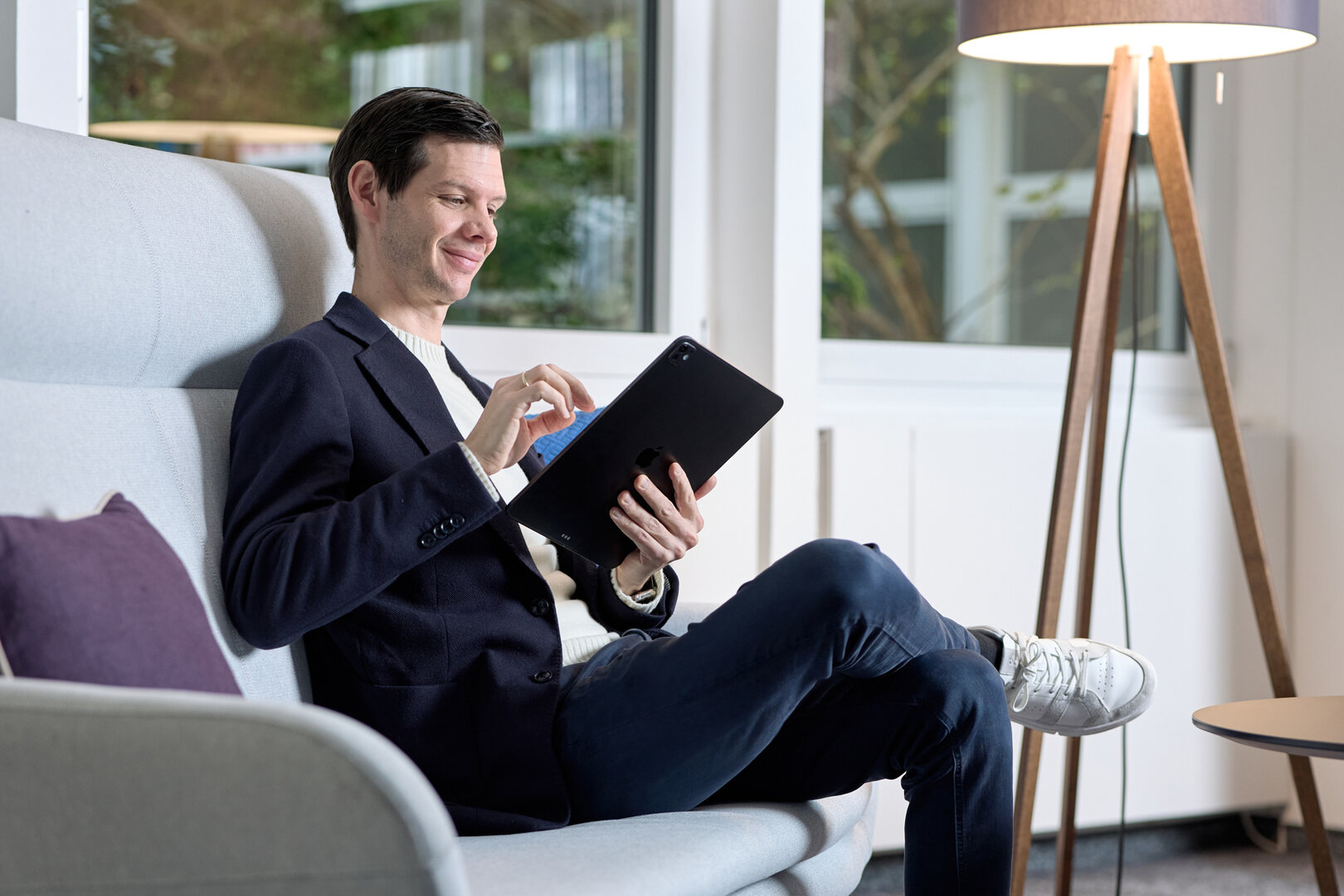 Mann im dunkelblauen Jackett schaut auf sein Ipad, Querformat